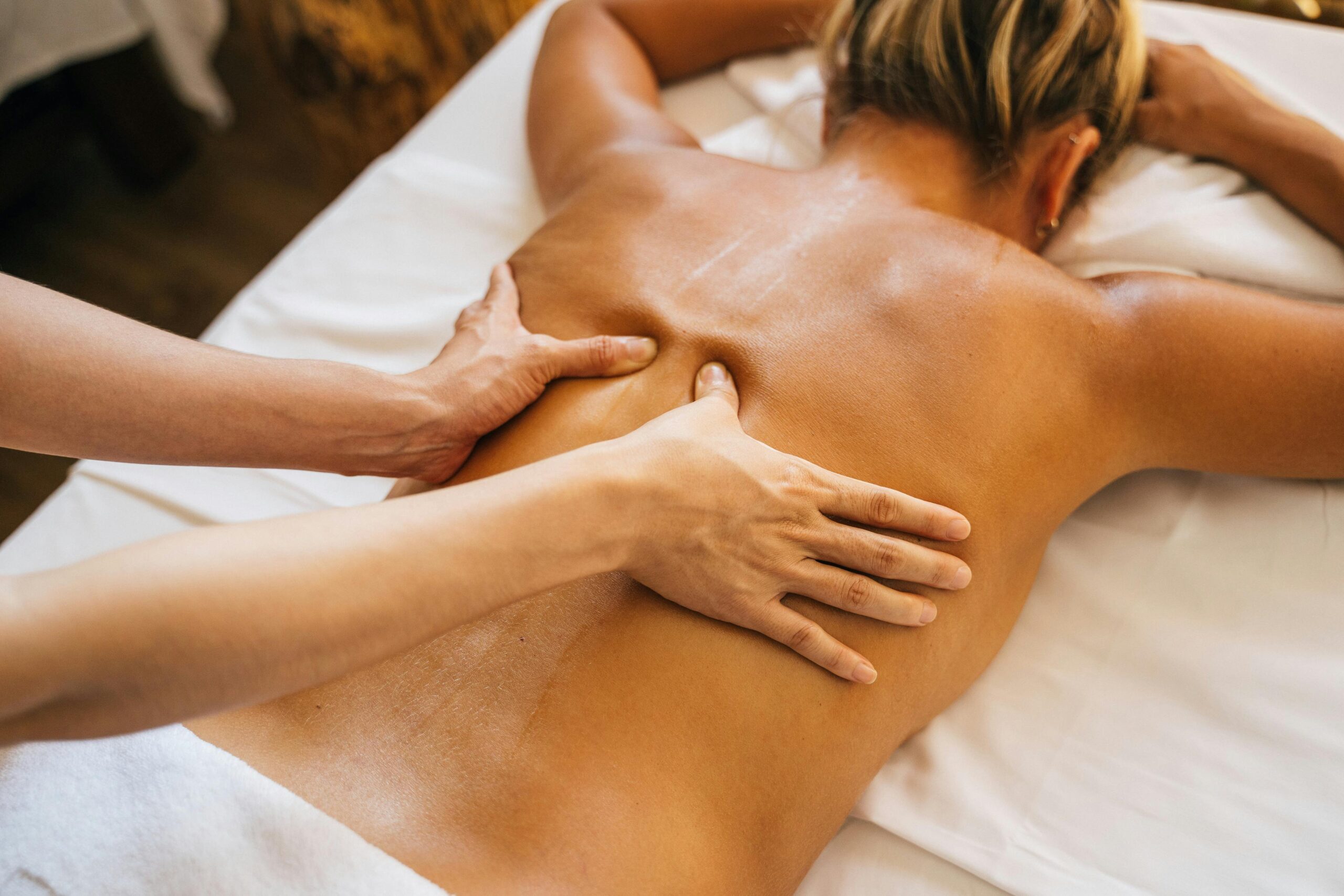 Massage thérapeutique du dos pratiqué par un professionnel sur une cliente dans un environnement relaxant