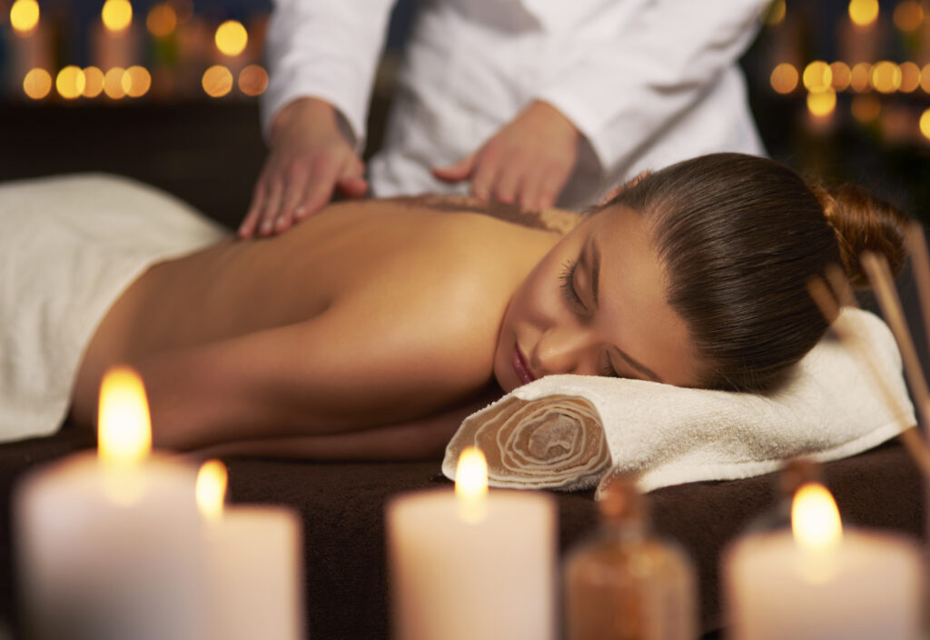 Séance de massage du dos pour une femme détendue dans un spa éclairé à la bougie avec ambiance tamisée